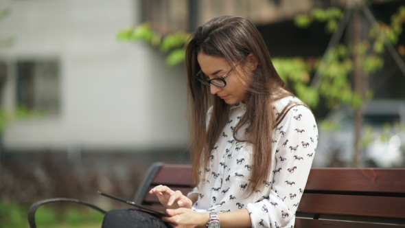 Beautiful Student In Glasses With a Digital Tablet Sitting Outdoor
