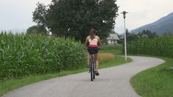 Young Girl Riding Bicycle On Rural Road