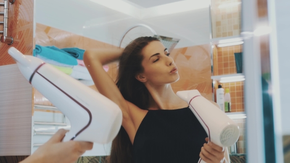 Brunette Young Girl Dancing With Hairdryer At Mirror In Bathroom. Happy. Smile alt