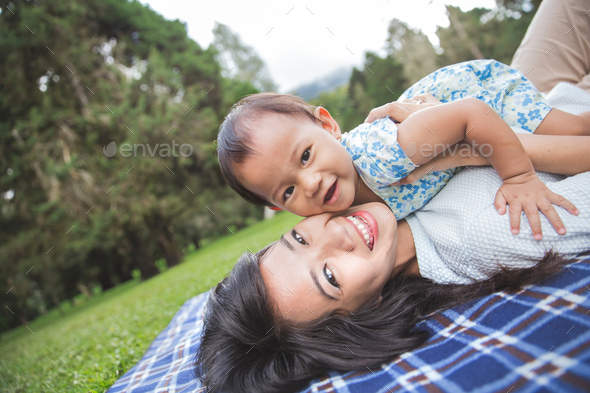 mom and daughter in happines laying on a grass