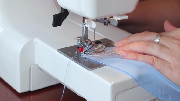 The Woman Begins To Sew On The Sewing Machine. Women's Hands. .