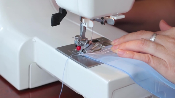 The Woman Begins To Sew On The Sewing Machine. Women's Hands. . alt