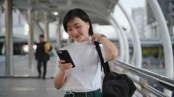 Portrait of happy asian woman with earphone listening music and using smartphone dance