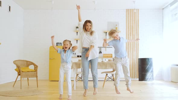 Young Mother with Two Children Dancing and Having Fun at Home in Living Room