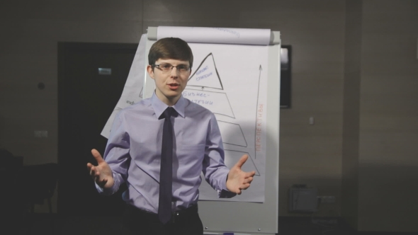 Handsome Young Man Pointing At Flipchart While Giving Presentation
