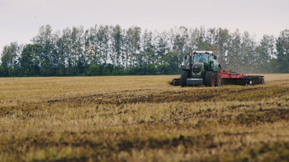 Tractor Plowing Land On The Field. A Flock Of Birds Flying Away alt