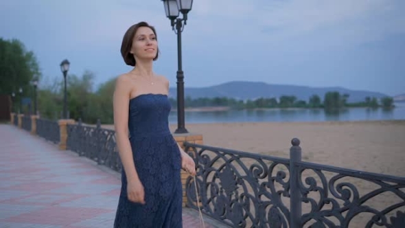 Active Young Woman Is Walking Briskly, In The Hands Of Her Handbag Golden Brown. alt