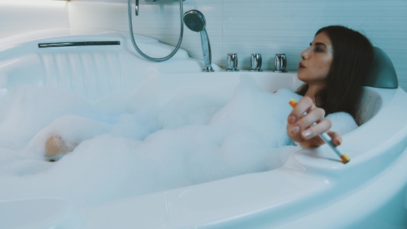 Young Girl Take Bath Full Of Foam In Bathroom. Smoking Electronic Cigarette alt