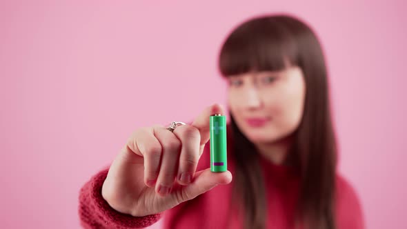 Young Woman Holding Batteries Isolated on Pink Background Pointing Forward alt