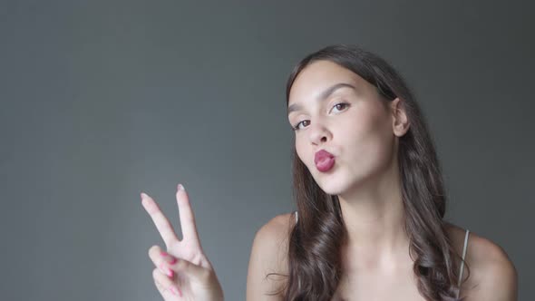 Young Brunette Female Flirting Kissing Showing Victory Sign on Camera Woman alt