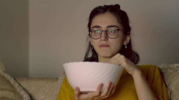 Teen Girl with Glasses Relax on the Sofa Eating Chips and Watching Tv in the Evening