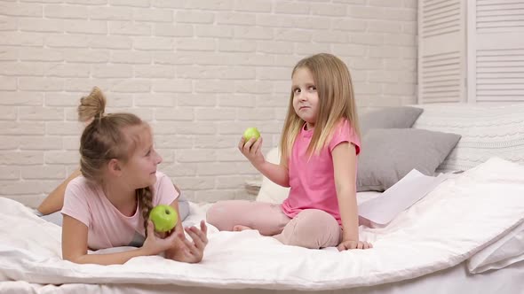 Two Little Children Girls Eat Green Fresh Apples
