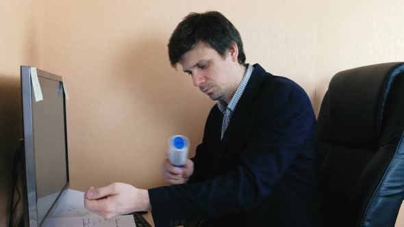 Young Man Cleans His Jacket with a Roller for Clothes Working at the Computer.