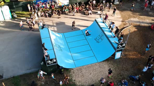 Male skateboarder doing tricks in an outdoor mini-ramp contest. alt