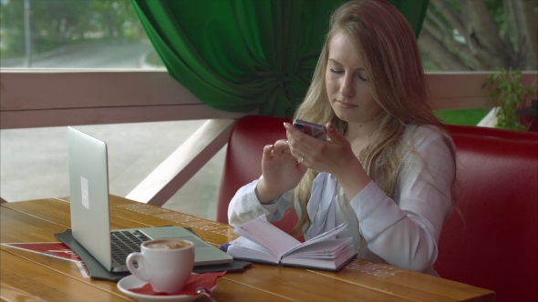 Business Woman In a Cafe Working With Smartphone Laptop And Notebook alt