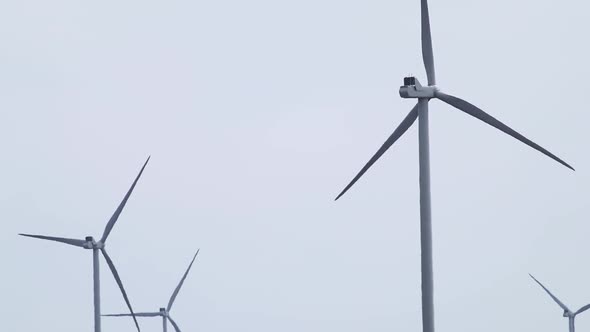 Wind generators farm close rotate on grey sky