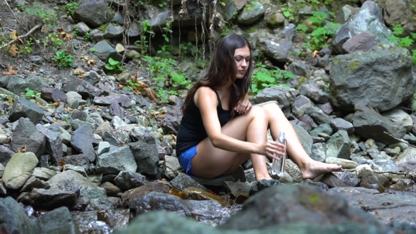 Girl Drinks Water On The Shore Of Mountain River