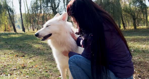 Happy Female Cheerfully Playing and Sitting with Dog in the Autumn Park. Love and Friendship with alt
