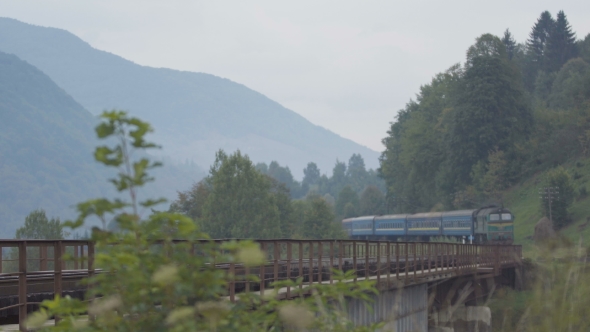 Passenger Train Passing Through The Bridge Over The Mountain River