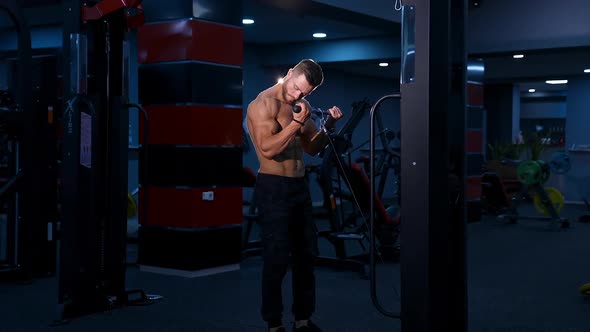 Shirtless male bodybuilder doing workout for hands in modern gym. Slow motion. alt