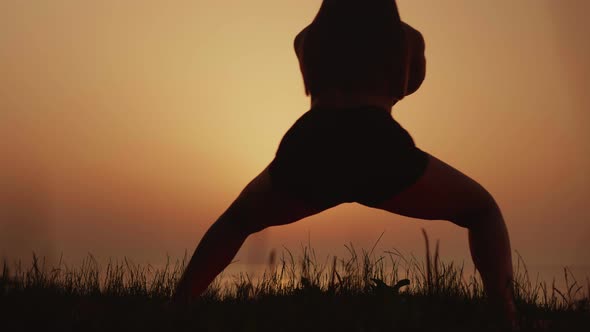 Woman Stretches Against the Background of a Beautiful Sunset