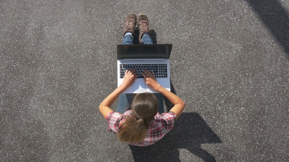 Girl Is Sitting On The Pavement With a Laptop