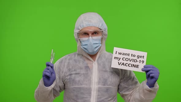 Doctor in Suit with Syringe Ampoule and Text Slogan on Paper  I Wand To Get My Covid19 Vaccine alt