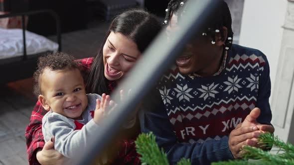 Multiracial Parents and Their Biracial Toddler Son Sitting By the Piano and Clapping
