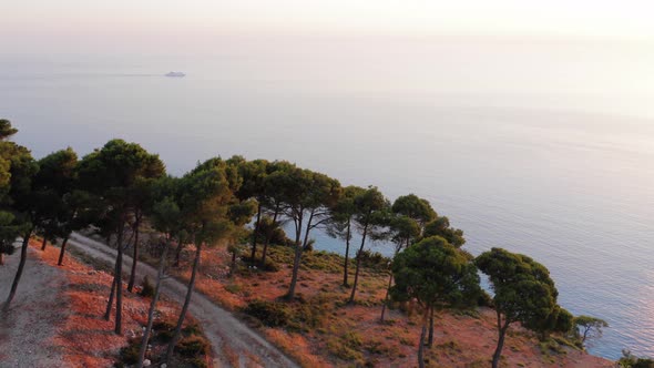 Aerial view of tall cliff by turquoise sea at sunset. alt