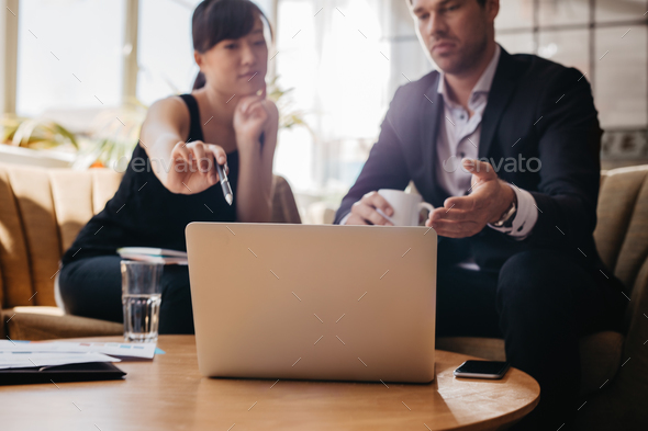 Woman presenting business idea on laptop to businessman - Stock Photo - Images