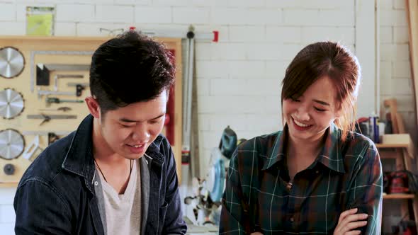 Two Carpenter man and woman are planning construction of built-in furniture in wood workshop alt