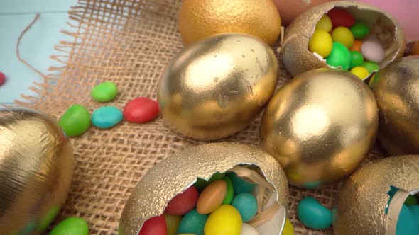 Golden Decorative Easter Eggs Filled with Colorful Candies on Wooden Table Close Up