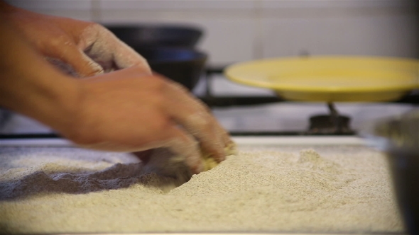 Baker Hands Kneading Dough In Flour On Table