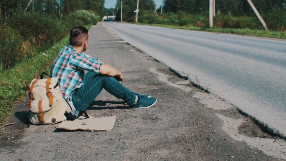 Man Sit At Road In Countryside. Hitchhiking. Waiting For Help. Pick Up Phone.