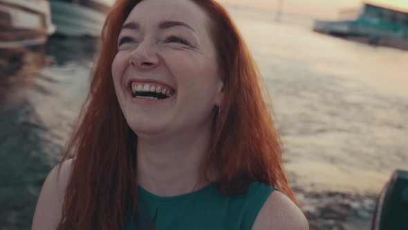 Attractive Red Hair Girl In Turquoise Dress On Motor Boat. Summer Evening. Laugh
