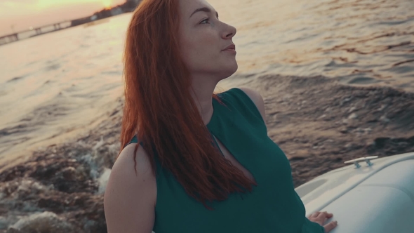 Pretty Red Hair Girl In Turquoise Dress Relax On Motor Boat. Summer Evening.