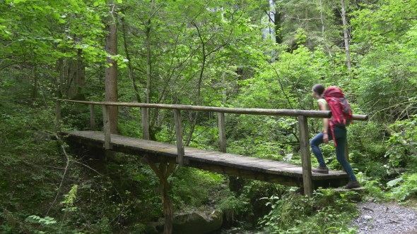 Hiker Woman Crosses Bridge Walking To Waterfall