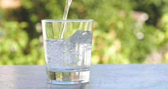 Pouring Fresh Pure Water Into a Glass in The Garden