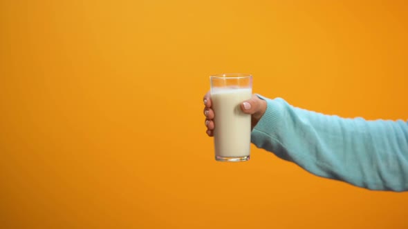Woman Hand Taking Offered Glass of Milk on Bright Background, Morning Energy alt