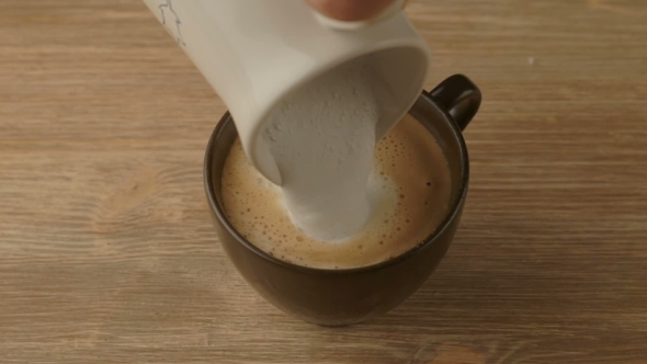Coffee Maker Pouring Hot Milk In Cup To Prepare Cappuccino