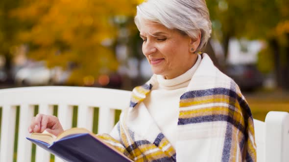 Happy Senior Woman Reading Book at Autumn Park 32 alt