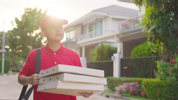 Asian deliver man worker in red color uniform handling bag of food, pizza give to customer girl. alt