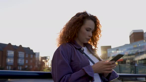 Young woman using smartphone in the city at sunset