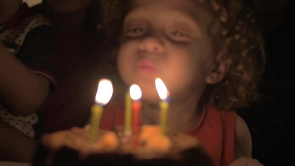 Child Blowing Candles On Birthday Cake alt