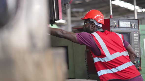 African American male factory worker operating  control machinery in construction site