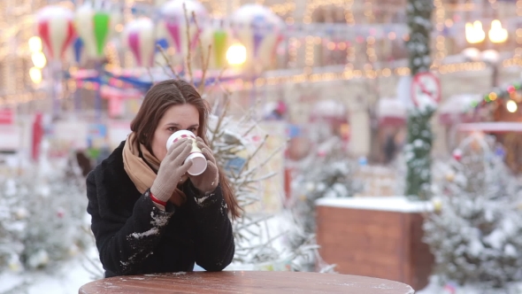 Beautiful Young Woman Drinking Hot Tea During Christmas Fair alt