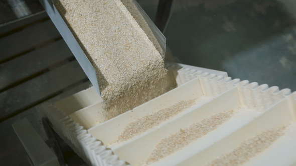 Cereal Oatmeal Crumbles Into Equal Shares In a Modern Automatic Machine. alt