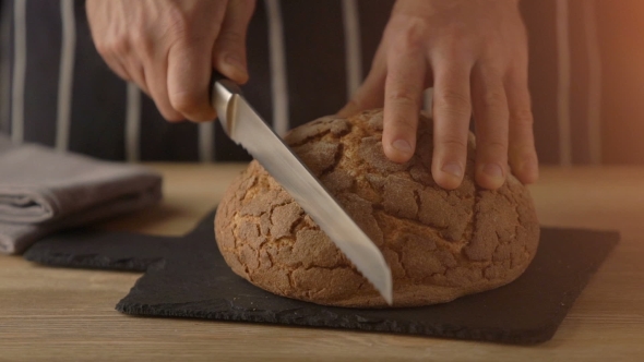 Chef Hands Slicing Home-made Bread On Wooden Table