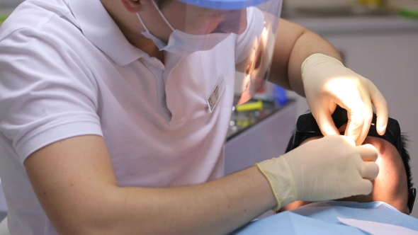 View Of Dentist Healing Male Client Teeth.