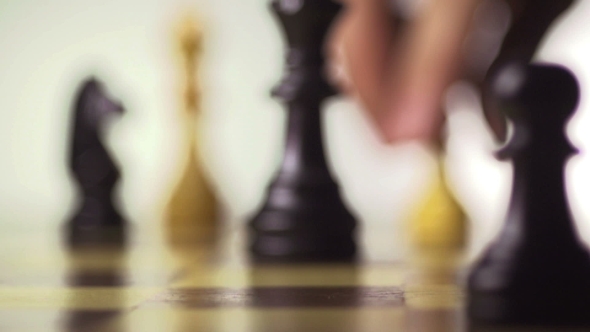 White Chess Player Knocks Down The Black King With His Piece alt